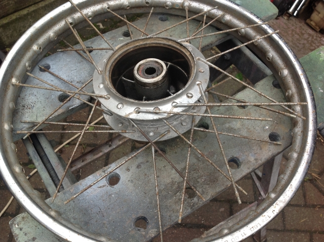 a dirty and rusty old wheel with broken spkes